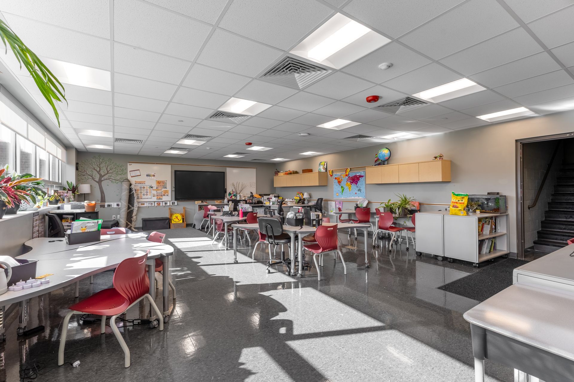 State College Area School District North Building's bright classroom with tables, chairs, colorful posters, and sunlight streaming through windows