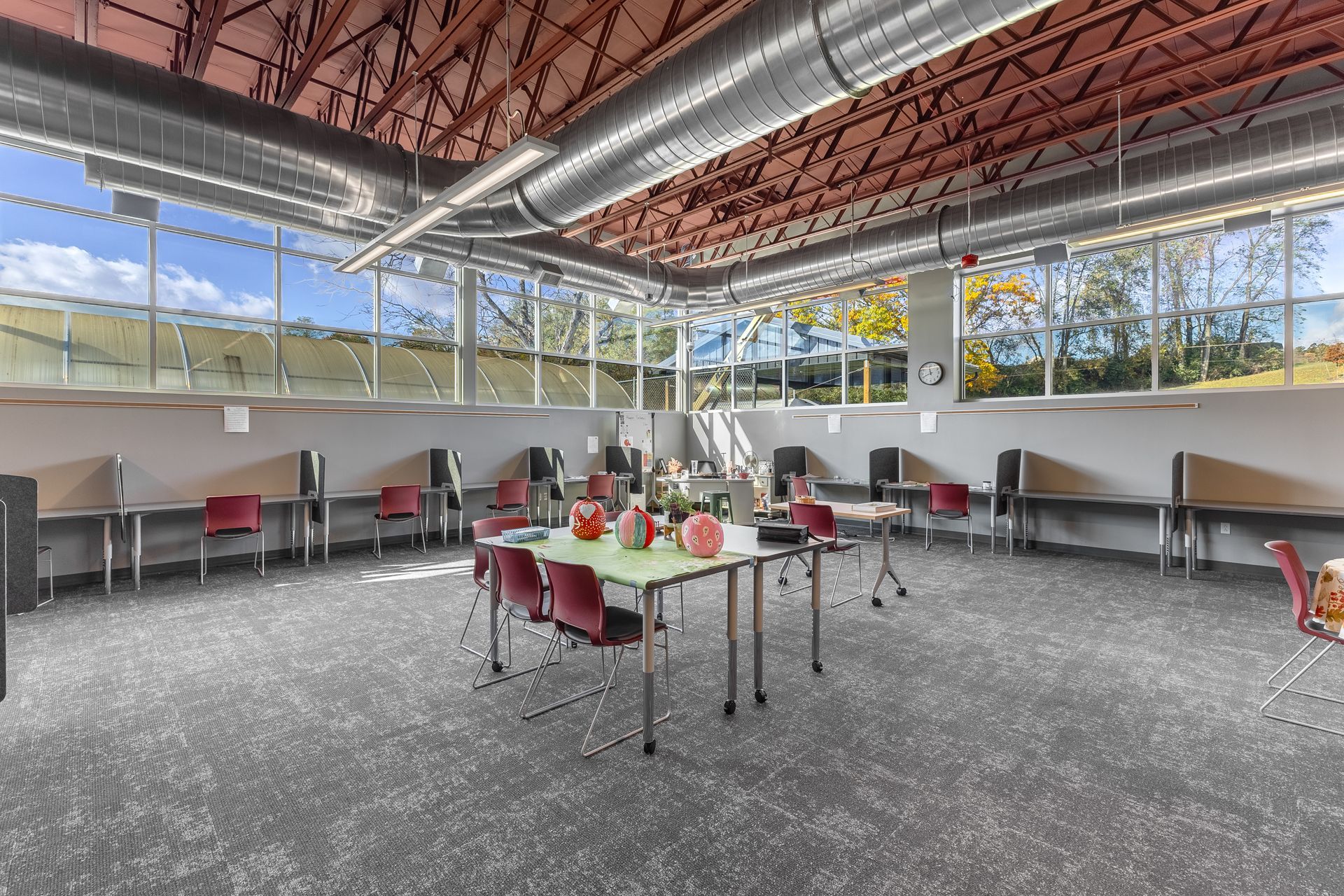 State College Area School District North Building's modern classroom with scattered tables and chairs, large windows, and a high exposed ceiling