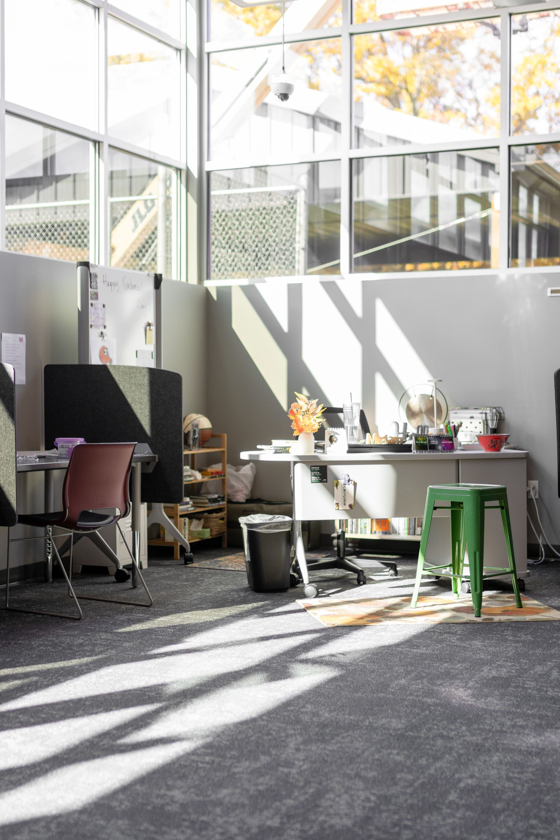 State College Area School District North Building's sunlit courtyard with tables, chairs, and potted plants beside a glass building wall