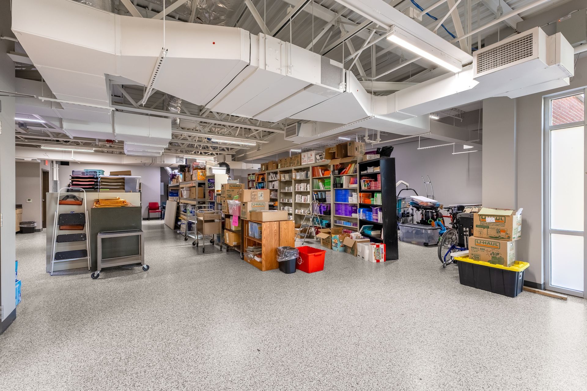 State College Area School District Panorama Village building's Spacious workshop with shelves of tools, boxes, and equipment under bright overhead lights
