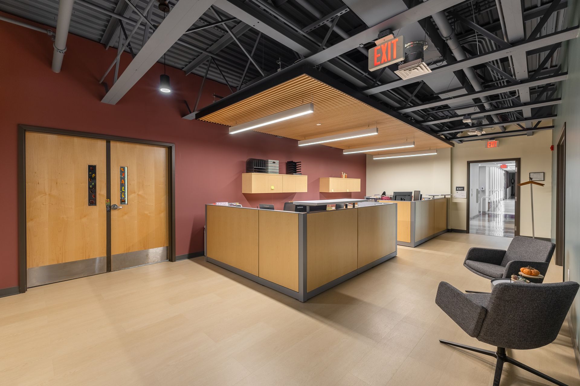State College Area School District Panorama Village building's modern office lobby with reception desk, glass doors, and black chairs under wood slat lighting