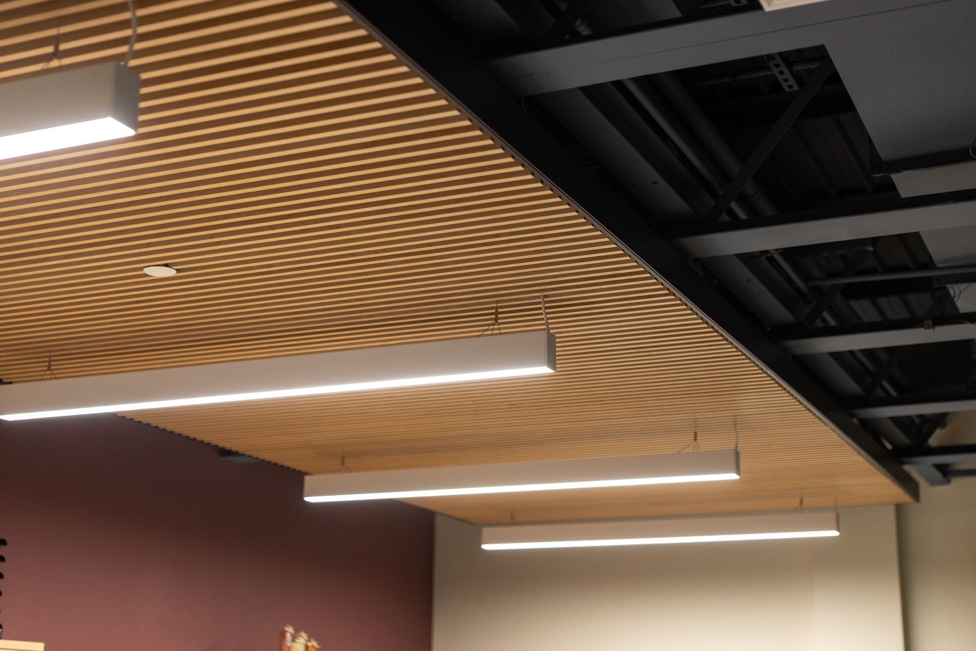 State College Area School District Panorama Village building's modern ceiling with wood slats and linear pendant lights in an indoor space