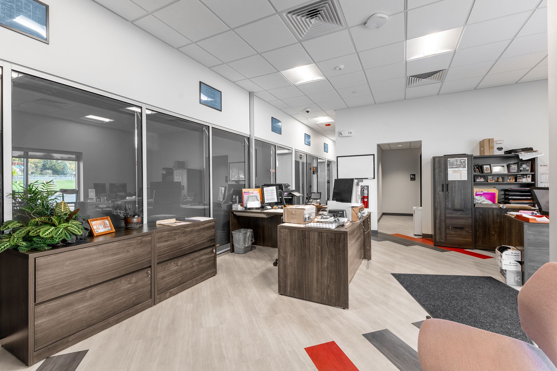 State College Area School District Physical Plant Building's lobby with desks, glass partitions, plants, and a reception counter