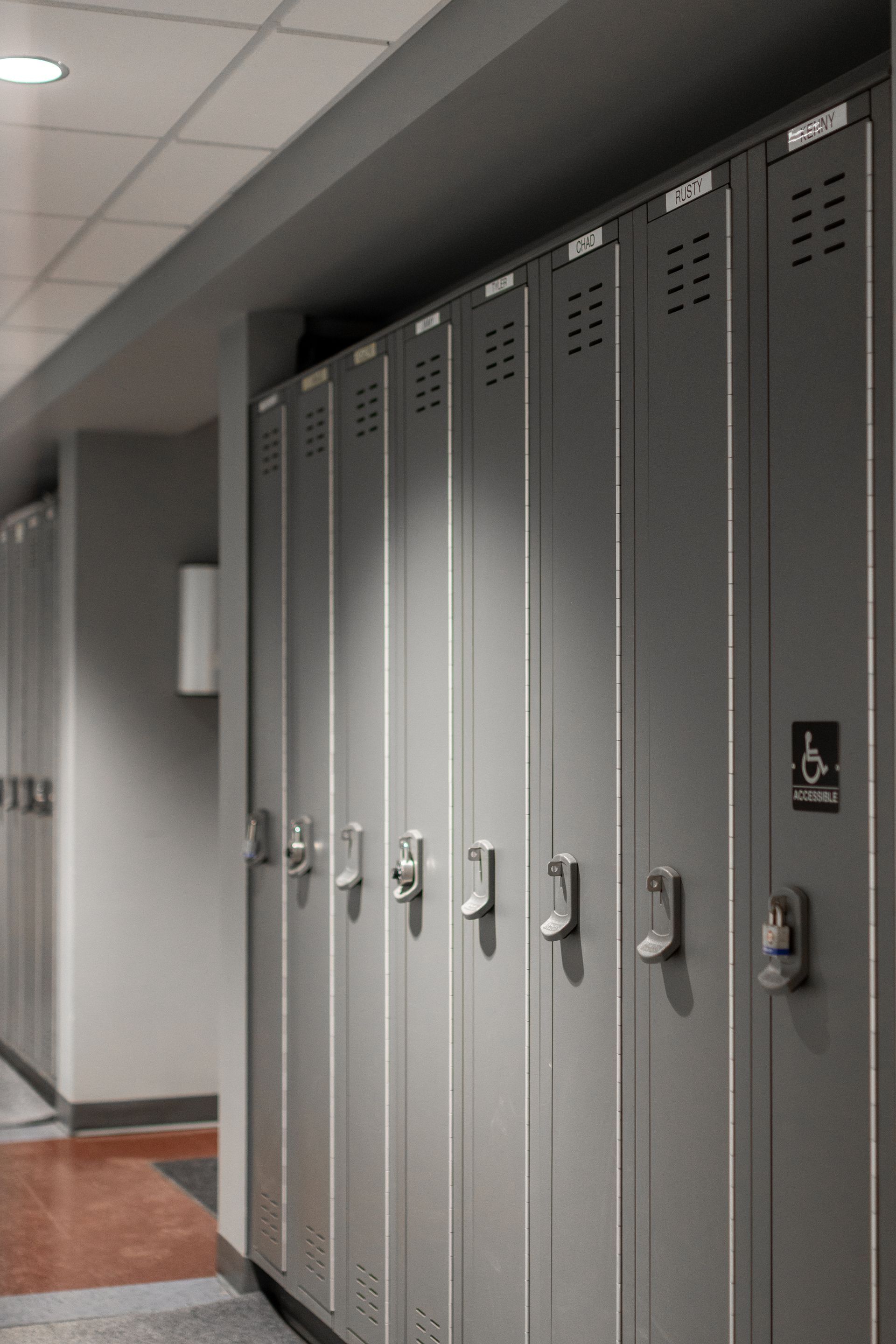 State College Area School District Physical Plant Building's row of gray metal lockers in a hallway, with an accessible locker sign on the right