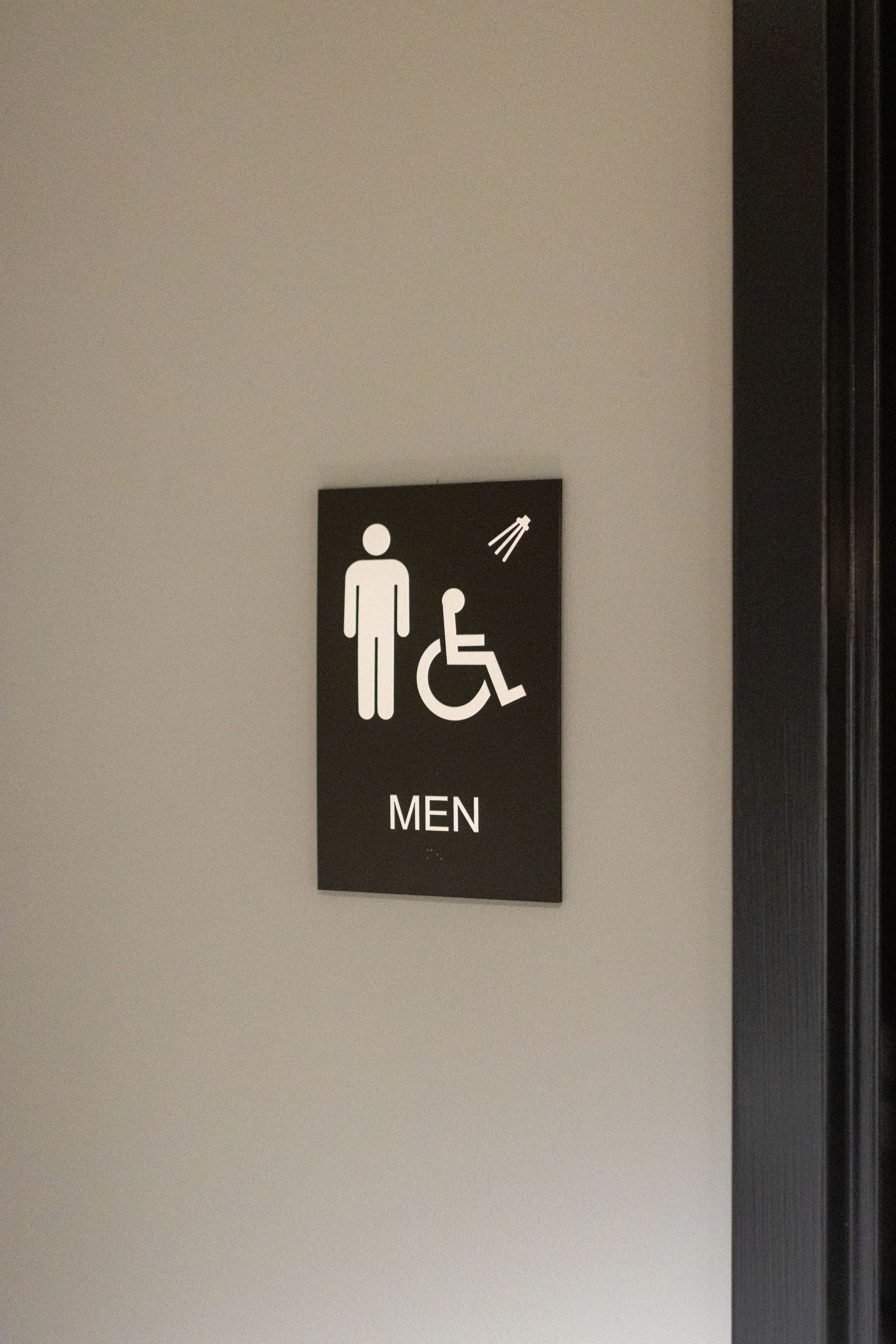 State College Area School District Physical Plant Building's restroom sign with wheelchair accessibility symbol on a wall.