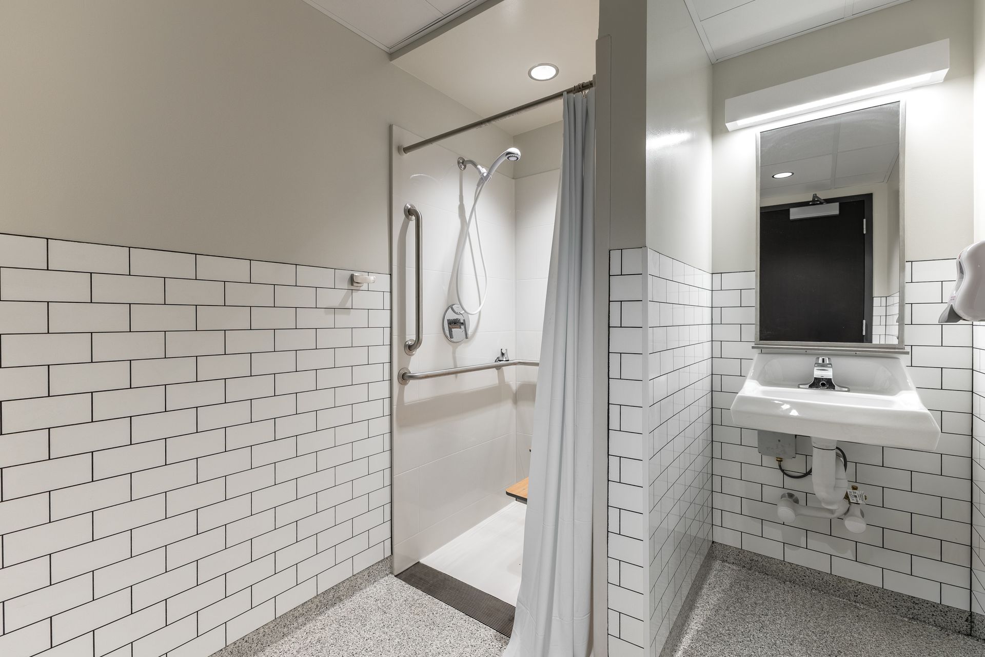 State College Area School District Physical Plant Building's modern bathroom with shower, sink, and black-and-white tiled walls and floor
