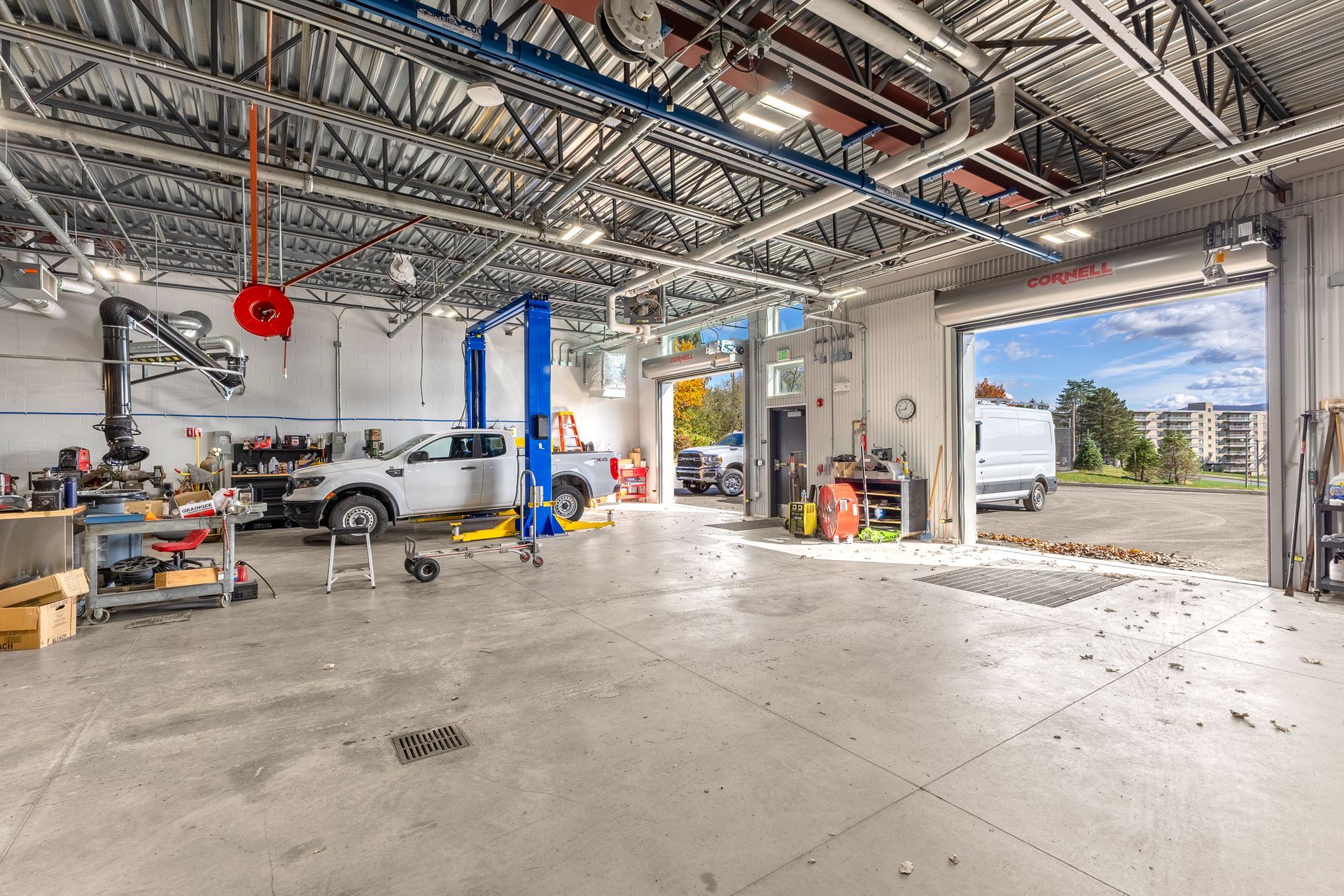 State College Area School District Physical Plant Building interior with car lift, tools, and large open garage doors