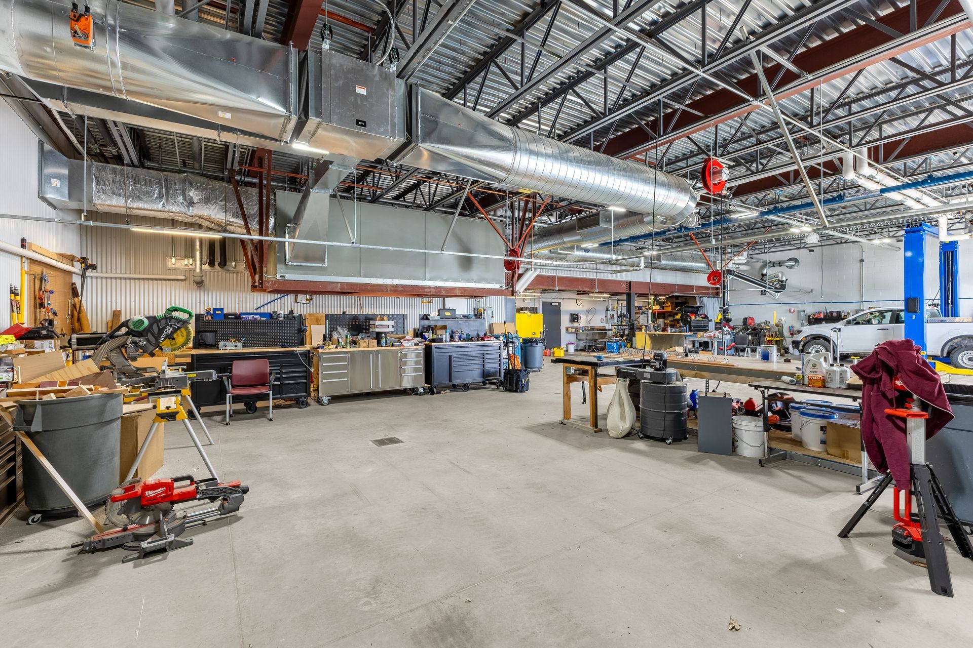 State College Area School District Physical Plant Building's workshop interior with exposed ducts, tools, workbenches, and a polished concrete floor