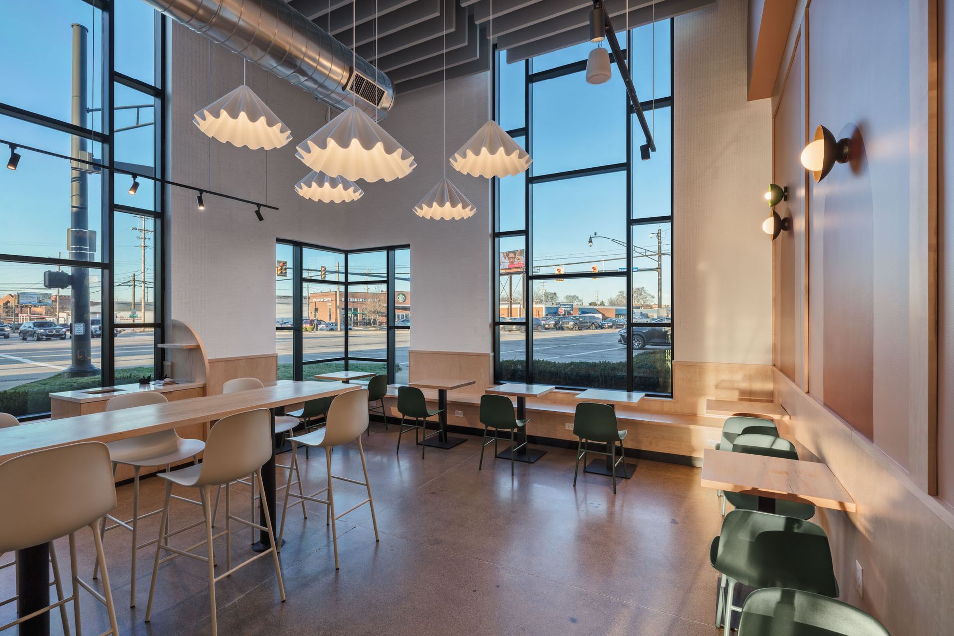 Roots Natural Kitchen interior with floor-to-ceiling windows, high-top tables, bar stools, pendant lighting, and neutral decor.