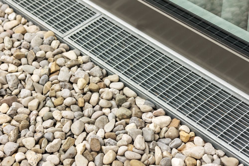 A metal grate is sitting on top of a pile of gravel.