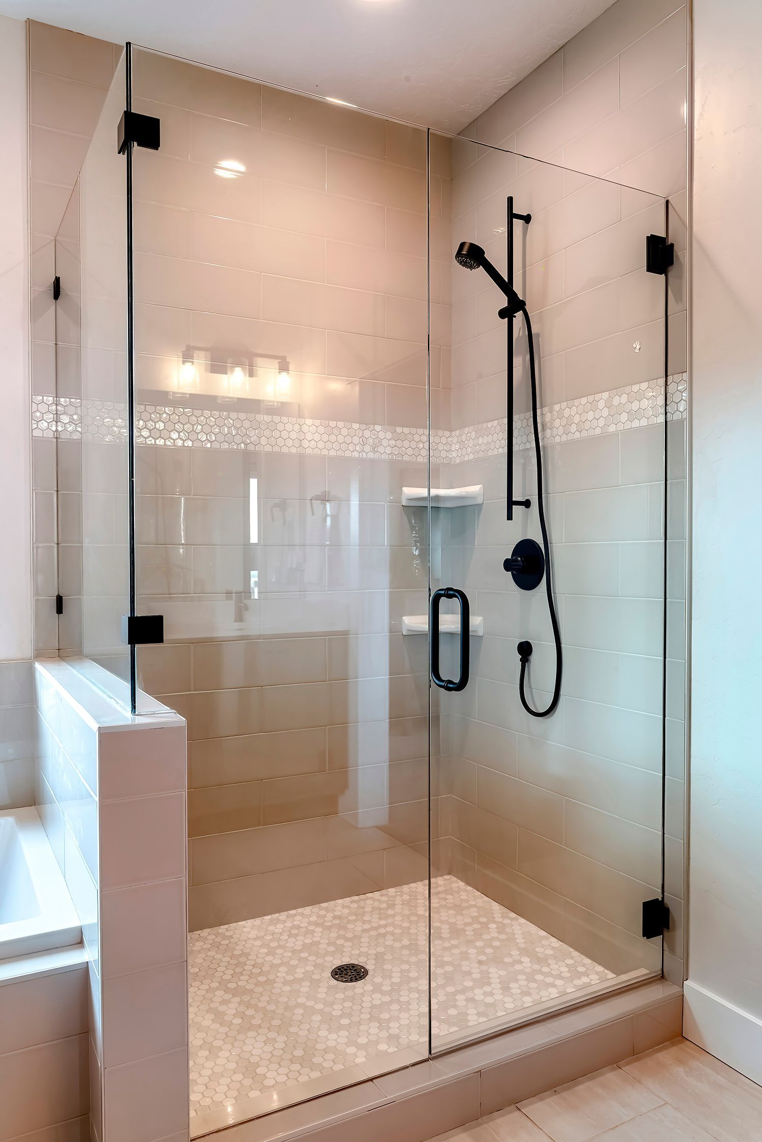 Frameless glass shower door with black hardware and modern tile walk-in bathroom design.