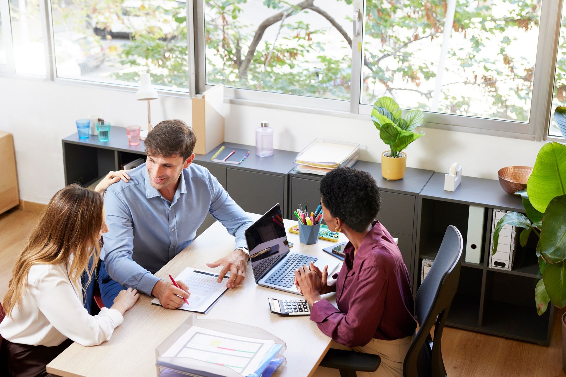 Local Insurance Agency agent helping a couple review and sign coverage paperwork at an office desk.