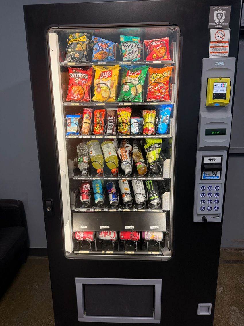 Black vending machine with snacks and cold drinks, front view.