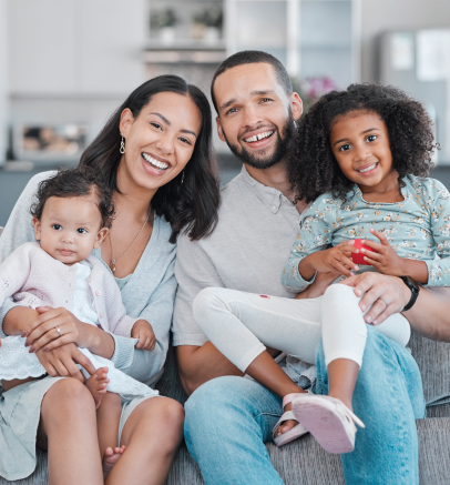 A family is sitting on a couch holding a drawing of their family.