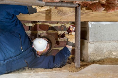 Home inspector examines a crawlspace that has a silver and thin steel pipe.