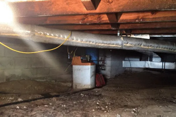 A crawl space beneath a building showing exposed wooden beams, a concrete block wall. A crawl space beneath a building showing exposed wooden beams, a concrete block wall.