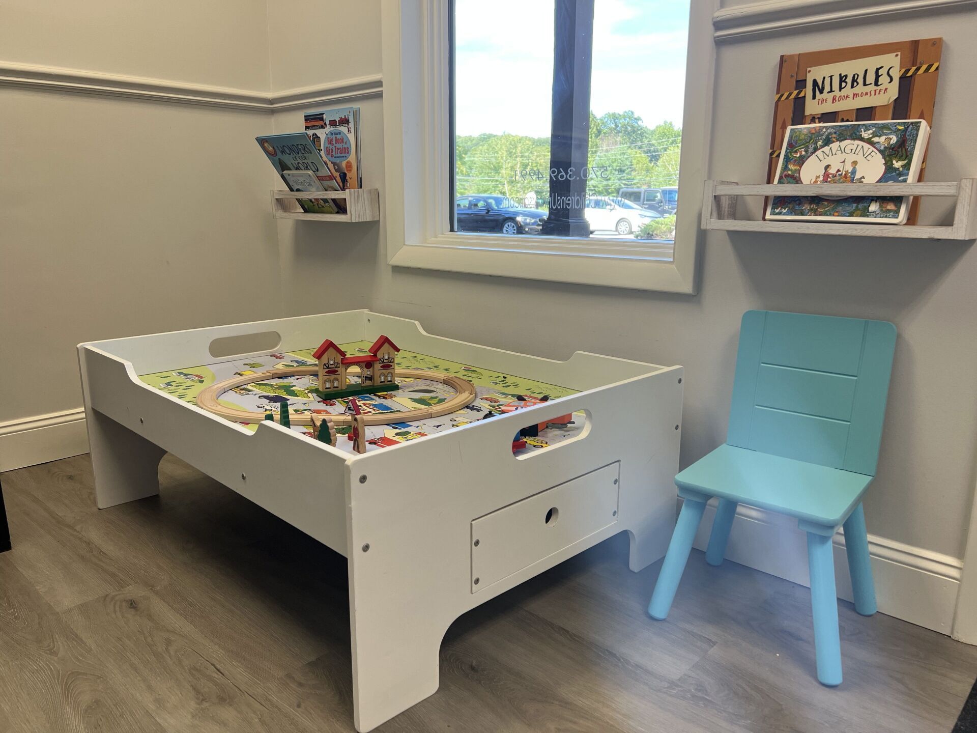 There is a table with a train on it and a chair in the room.