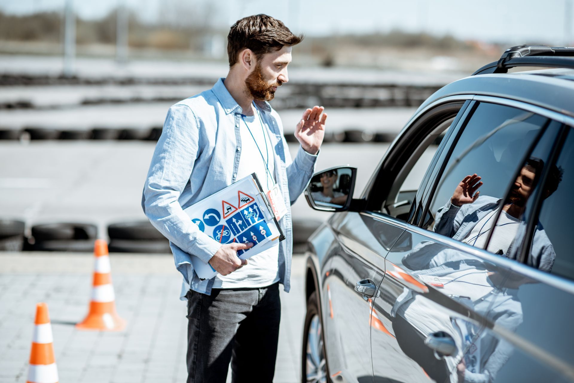 Driving instructor talking to a driver in a car. Outdoor driving course setting. Driving instructor talking to a driver in a car. Outdoor driving course setting.