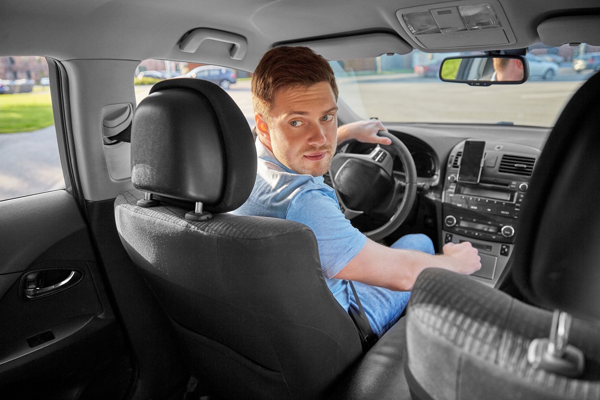 Man in a car, looking back over his shoulder while holding the steering wheel. Man in a car, looking back over his shoulder while holding the steering wheel.