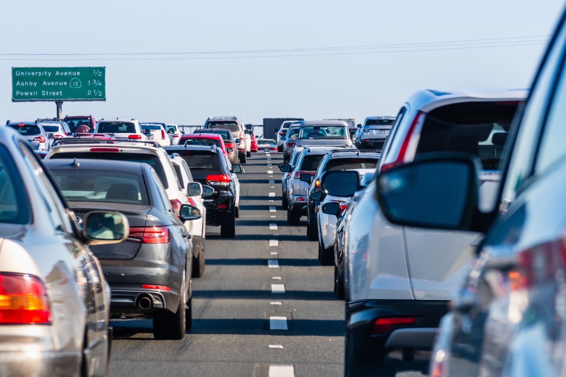 Cars in heavy traffic on a multilane highway, a green sign in the background. Cars in heavy traffic on a multilane highway, a green sign in the background.
