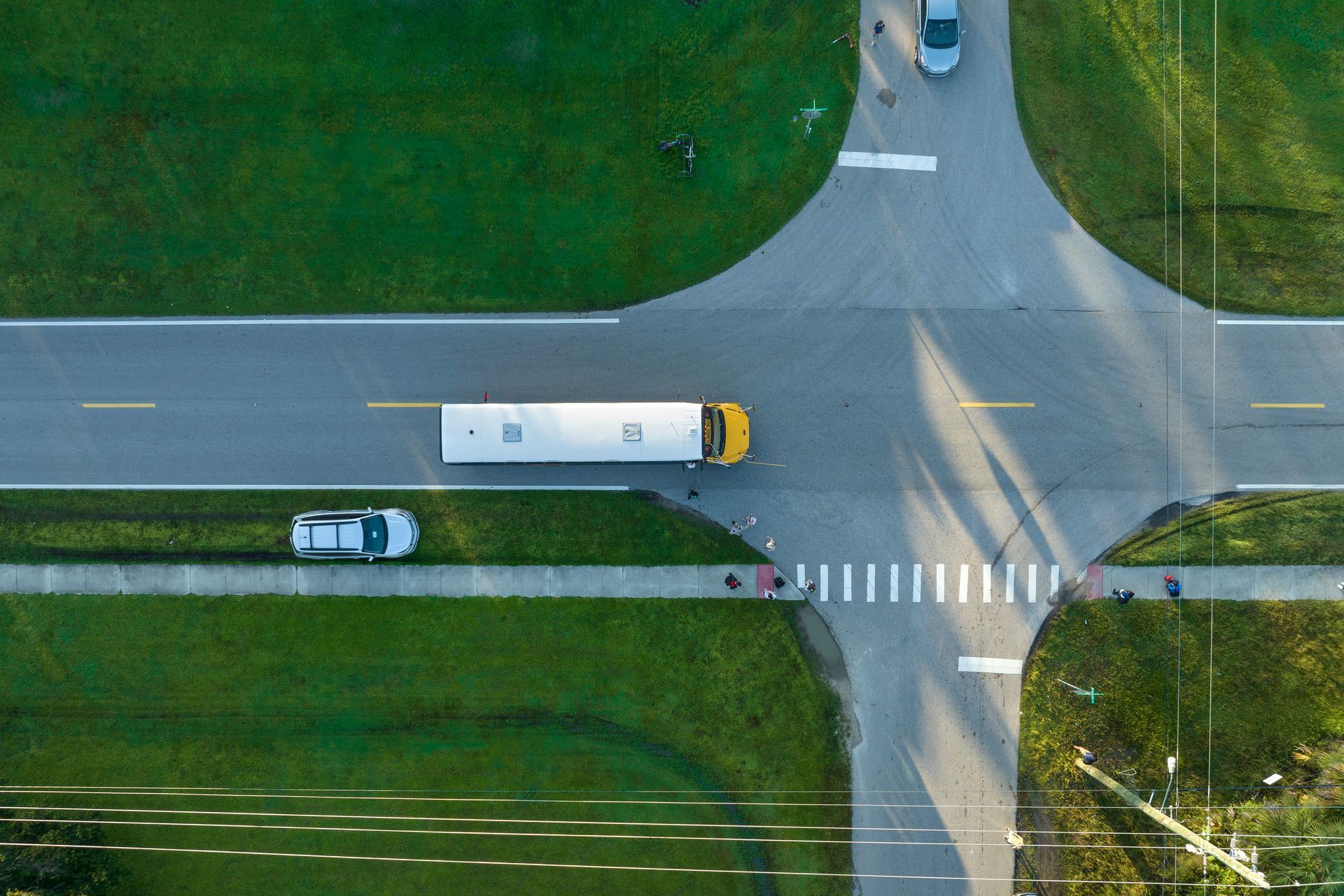 Overhead view of a school bus traveling through a crossroads with a white car in the left lane.
