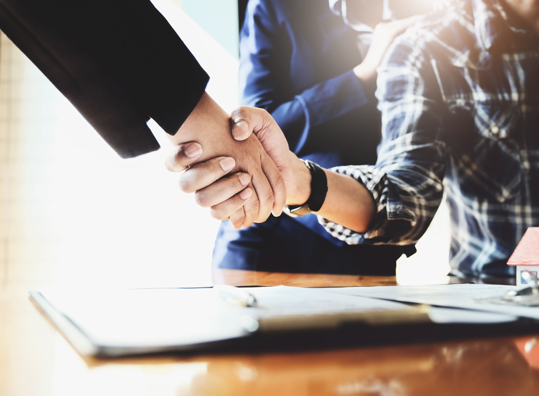A man and a woman are shaking hands over a table.