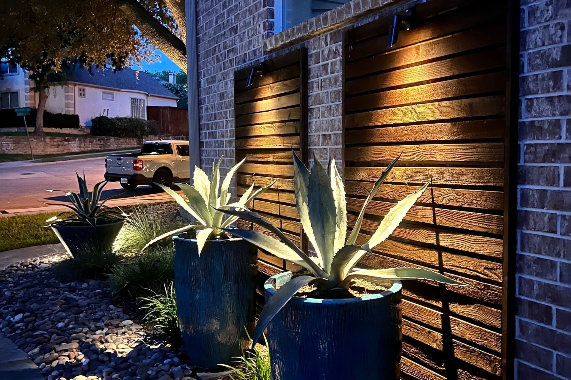 A couple of potted plants are sitting in front of a brick wall.