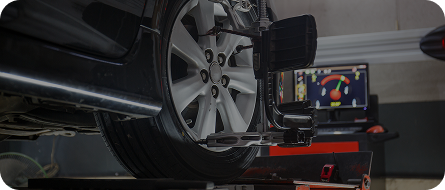 A black car wheel being aligned by a machine with a digital display. | GenAuto