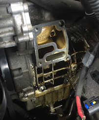 Engine component with a gasket removed, showing oil residue.