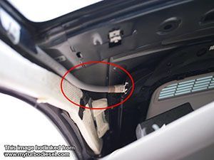 Gray tube inside a car's roof, likely part of the sunroof mechanism, with white fabric and black trim visible.
