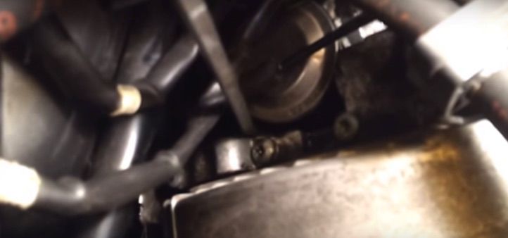 An engine's undercarriage with belts, hoses, and a metal pan.