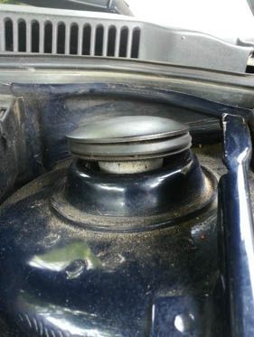 Dark blue car suspension component, close-up. Black rubber and metal parts visible. Dusty.