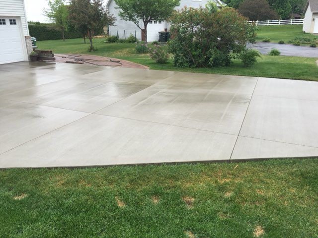 Empty concrete parking lot with painted lines and a chain-link fence in the background