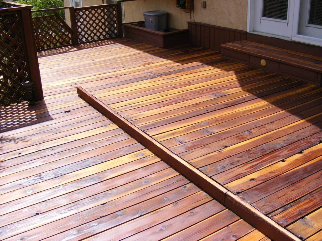 a wooden deck with a bench on the side of it
