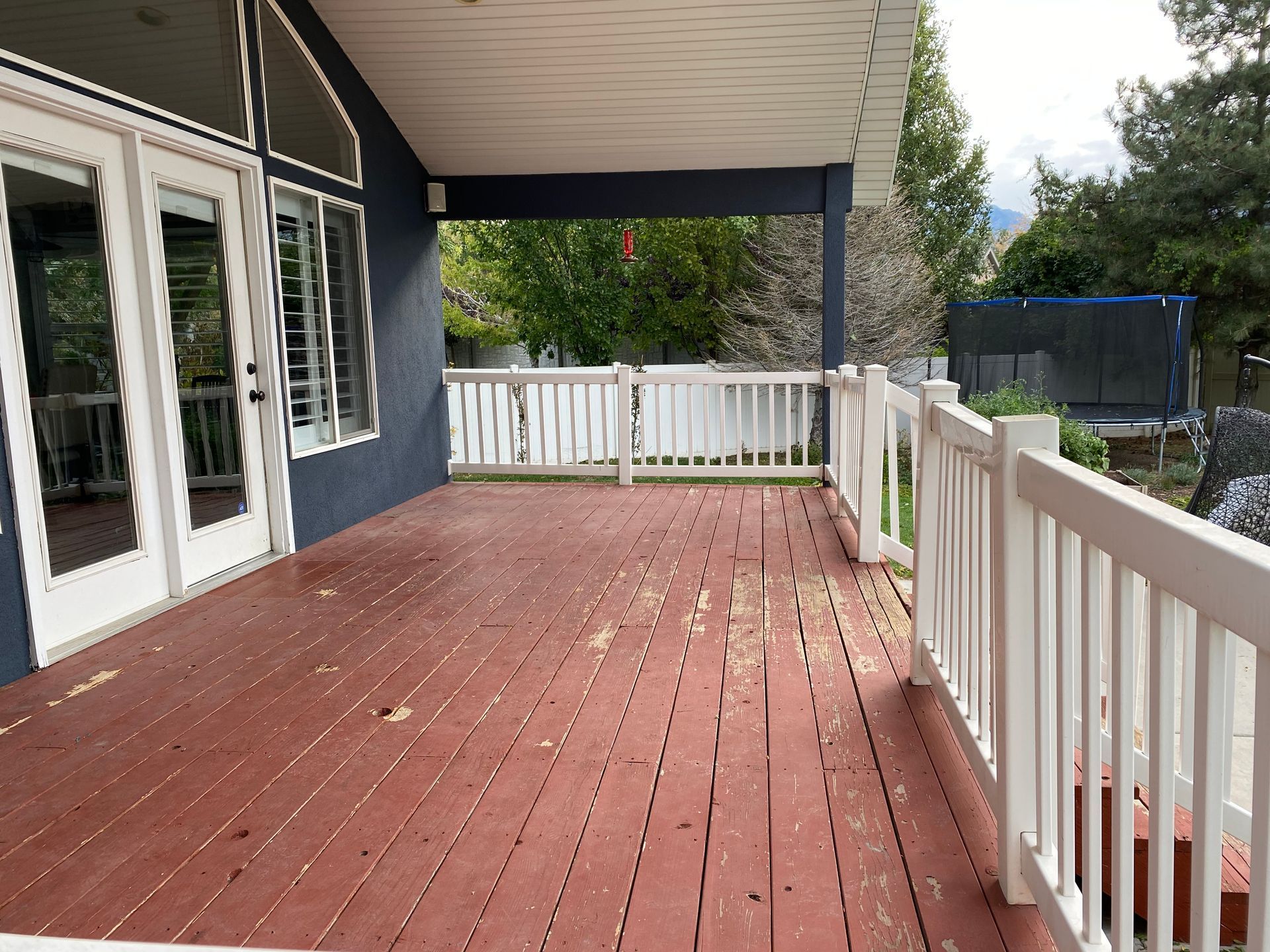 an empty deck with a white railing and a trampoline in the background .