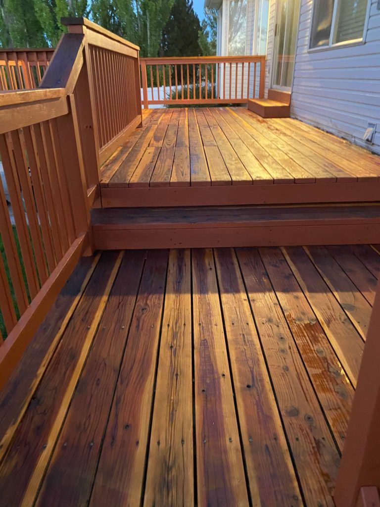 a wooden deck with stairs leading up to it next to a house .