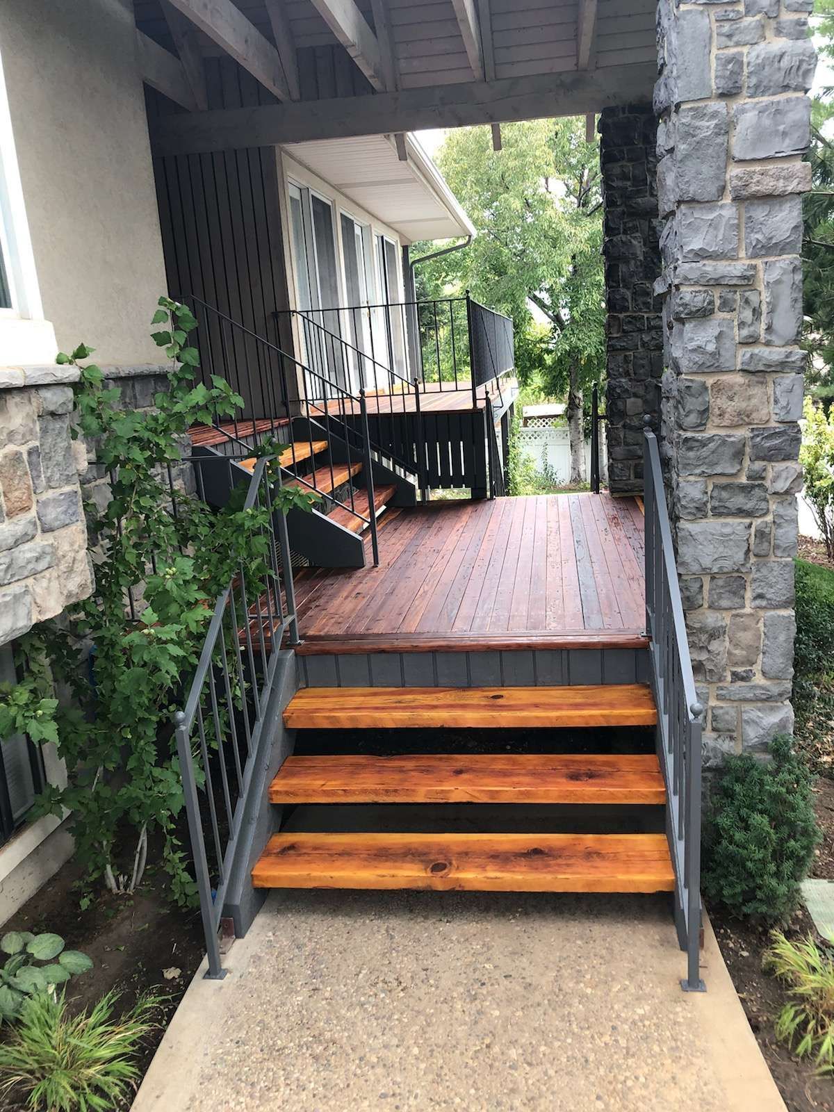 a wooden deck with stairs leading up to it and a stone wall .