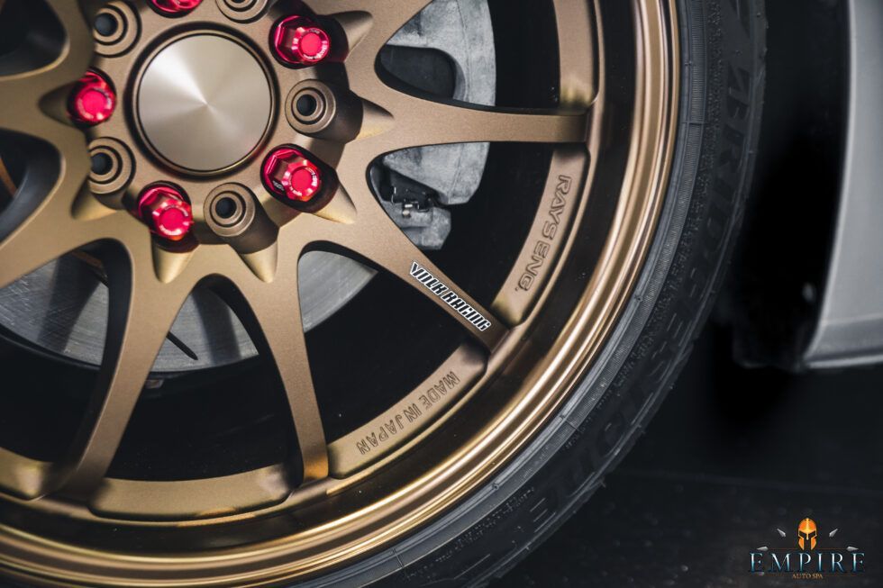 A close up of a car wheel with red nuts on it.