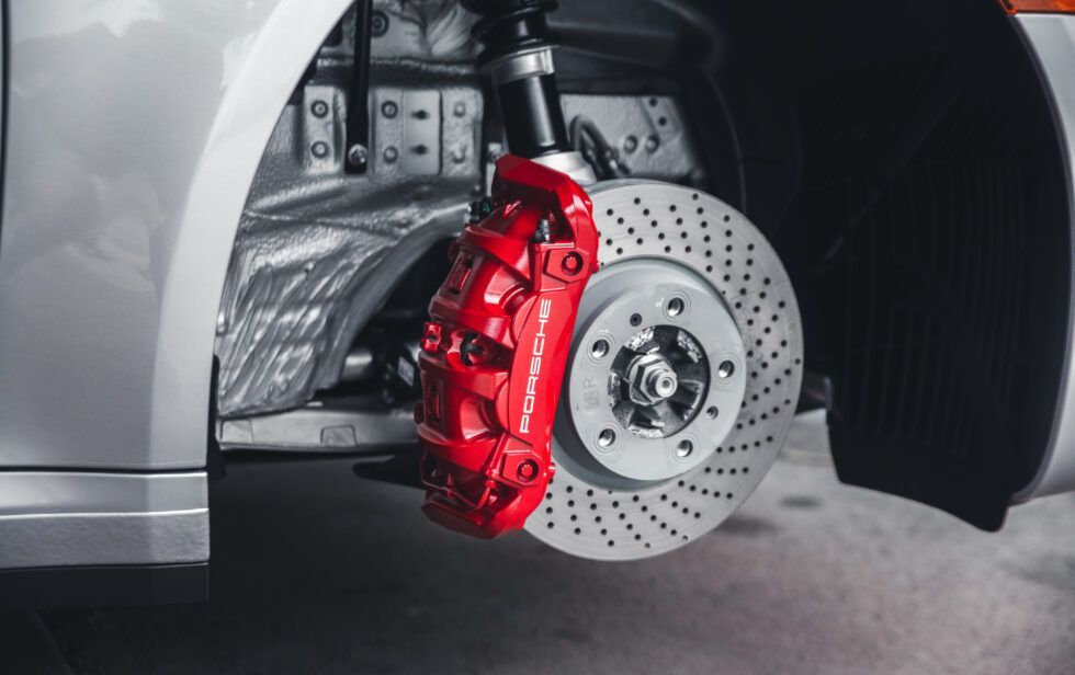 A close up of a car 's brake system with a red brake caliper.