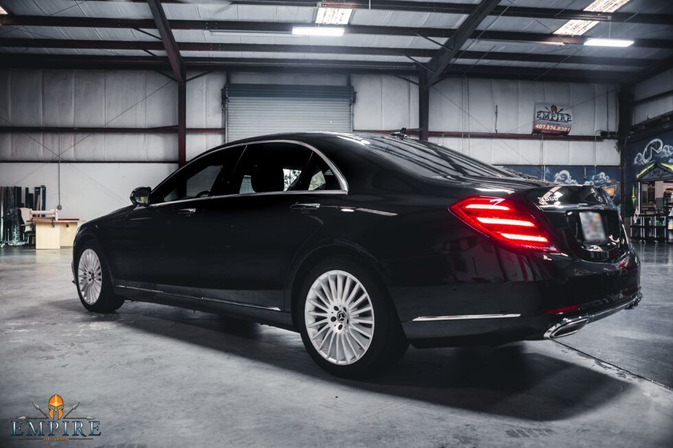 A black mercedes benz s class is parked in a garage.