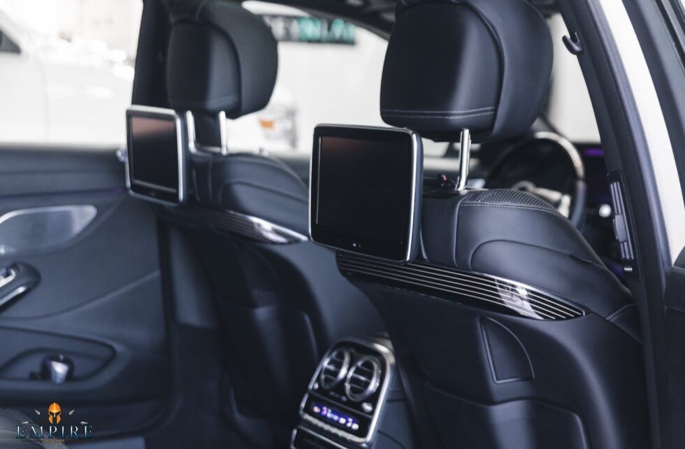 The back seat of a car with two headrest monitors.