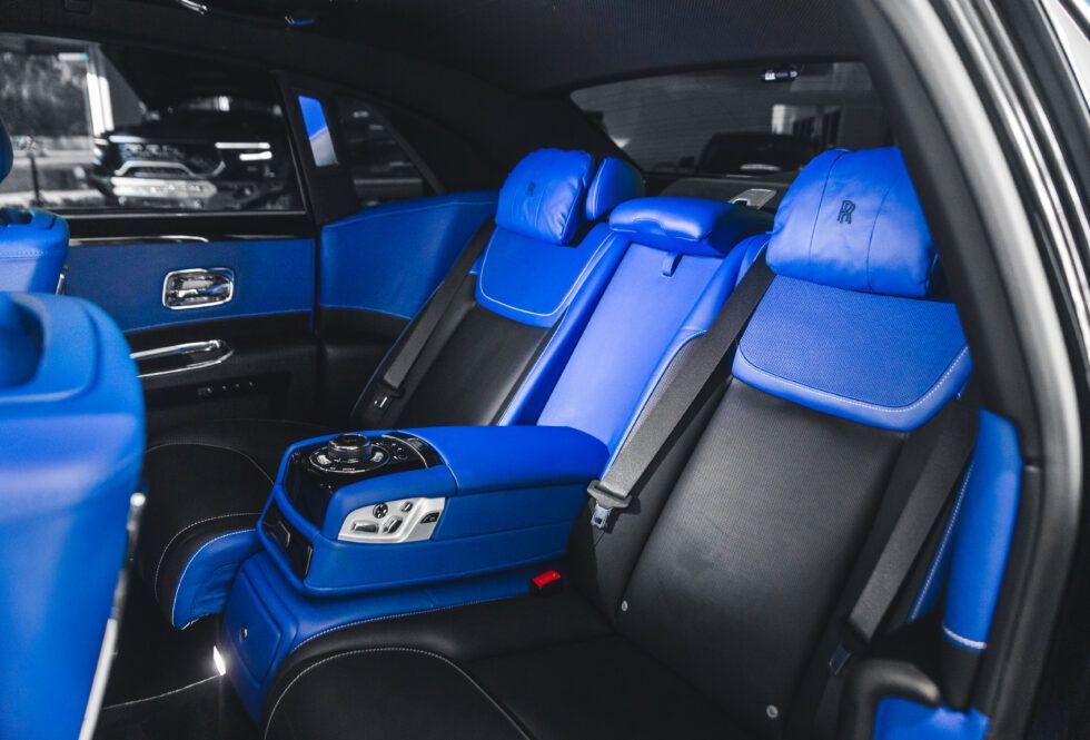 The back seat of a black car with blue seats