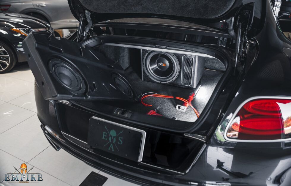 The trunk of a black car with speakers in it