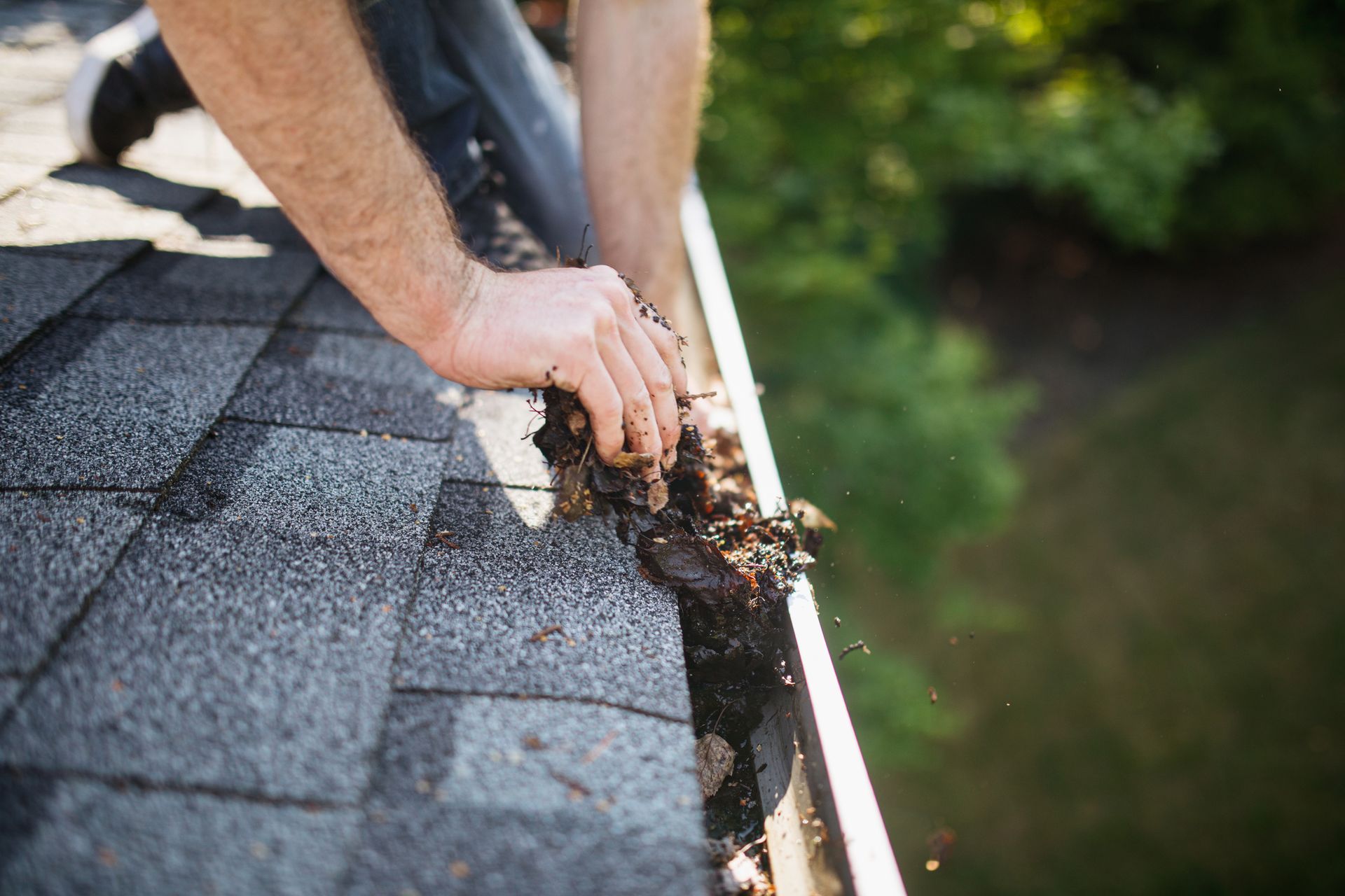 A man is cleaning a gutter on a roof.