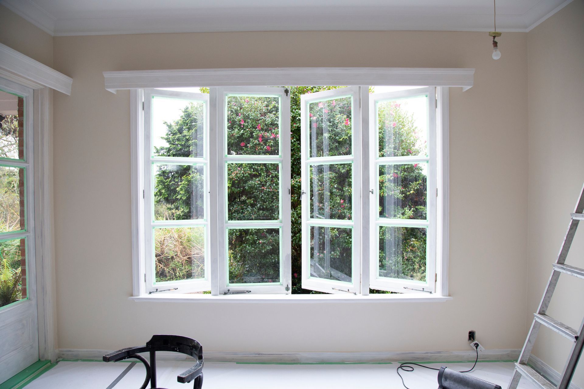 An empty room with a large window and a ladder.