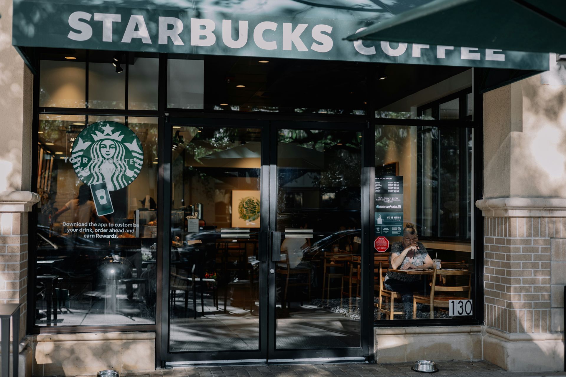 A starbucks coffee shop with people sitting at tables outside.