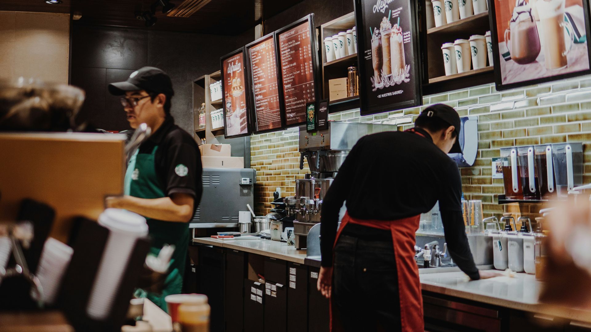 Two men are working in a starbucks coffee shop.