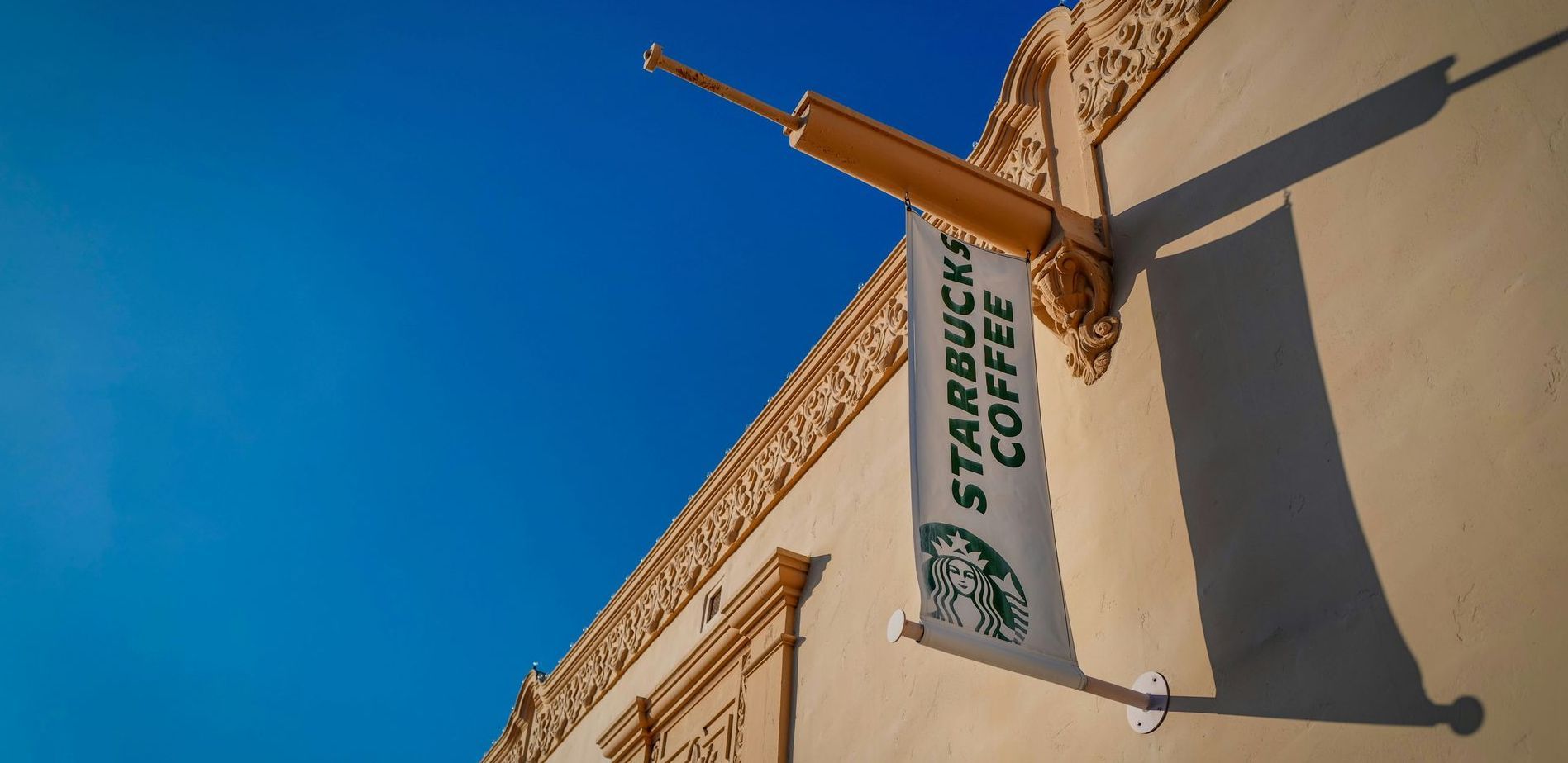 A starbucks coffee sign hangs on the side of a building