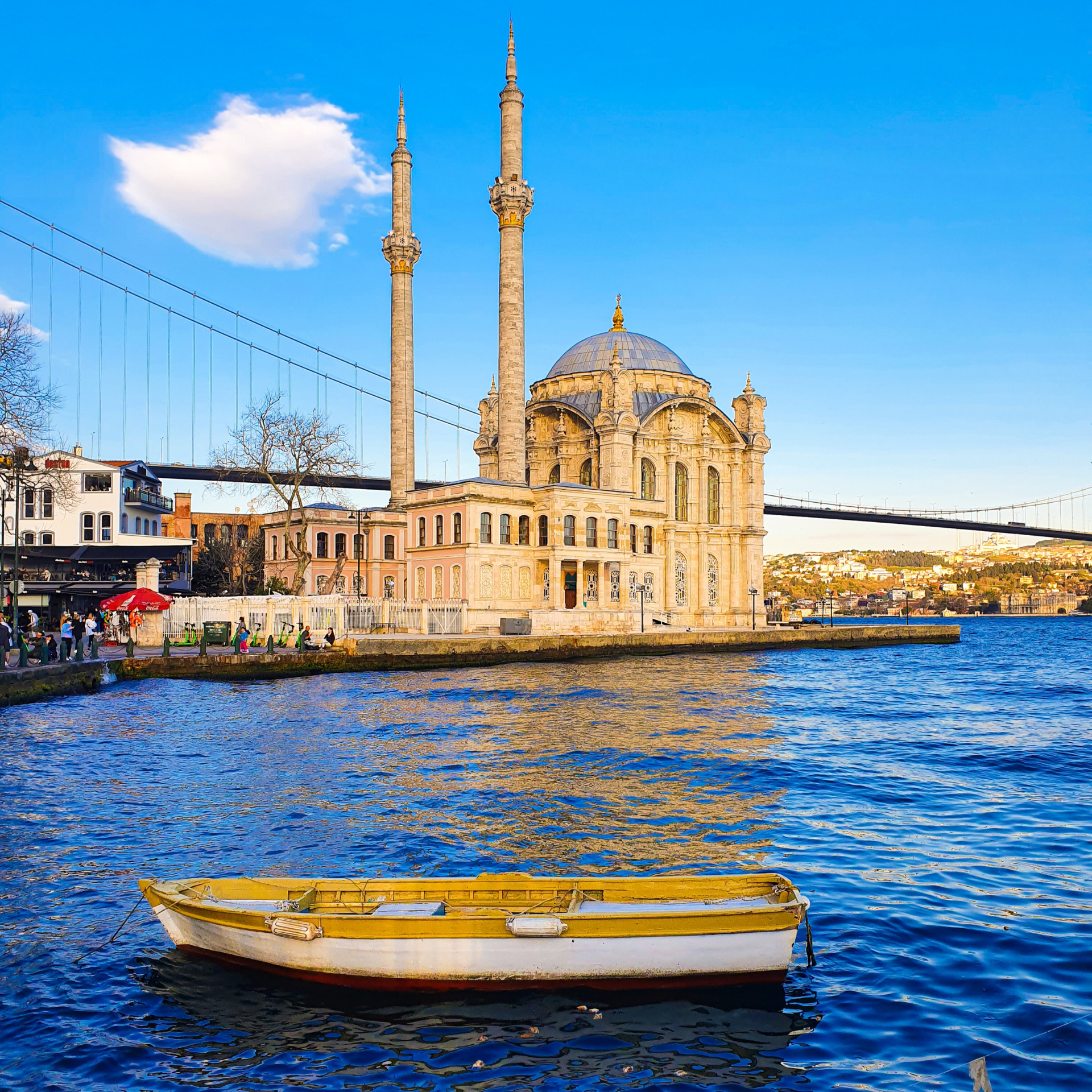 A boat is floating in the water in front of a mosque.
