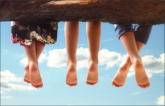 three children 's feet are hanging over a tree trunk